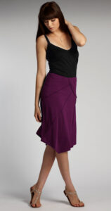 A plumb-colored sun-ray organic cotton skirt with a handkerchief point at the side.