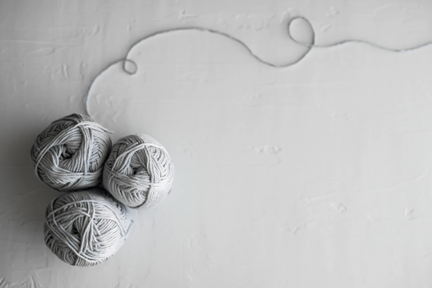 Three bundles of gray yarn on a white surface