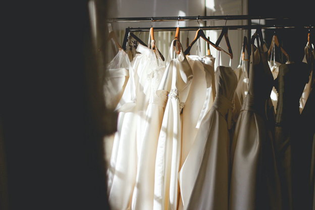 A variety of ethical wedding dresses on hangers.
